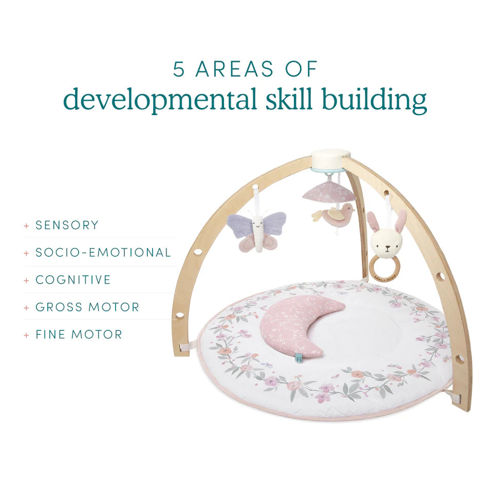 Ma Fleur Activity Gym with wooden arch and soft floral play mat featuring hanging butterfly, bird, and bunny toys designed to support sensory, socio-emotional, cognitive, gross motor, and fine motor skill development.