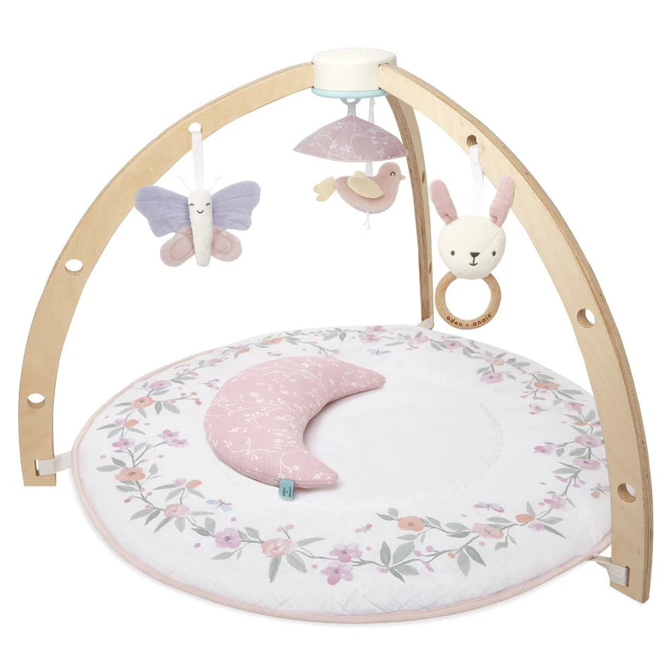 Ma Fleur Activity Gym with wooden arches, hanging plush butterfly, bird, and bunny toys, a floral print round mat, and a pink crescent pillow for baby play and development.